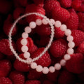 Two pink beaded bracelets on a bed of raspberries