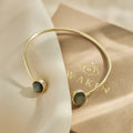 Gold bracelet with labradorite gemstones on a beige fabric background