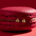 Gold earrings on a red macaron against a red background