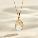 Gold pendant with a clear stone on a beige background