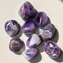 Purple amethyst crystals on a light surface with a soft shadow