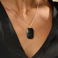 Woman wearing a black obsidian silver pendant necklace against a beige background