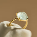 Gold ring with a fluorite gemstone on a beige fabric background