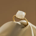 Gold adjustable ring with a large moonstone gemstone on a beige fabric background