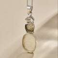 Silver pendant with embedded stones on a beige background